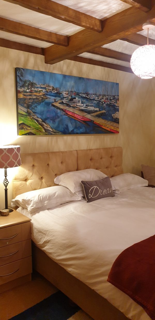 Photograph of bedroom showing scale of Durban Point Yacht Club painting against the headboard of a King size bed
