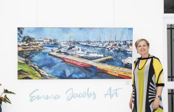 Artist Emma Jacobs standing next to her Point Yacht Club with Chinese dragon boats large painting mounted on a white wall