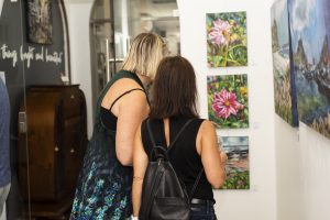 Two ladies looking at a series of paintings